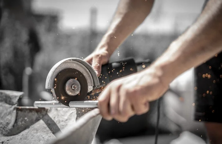 Person sägt Metallrohr mit einer Flex.